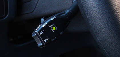 An image showing a cruise control switch through the opening in a steering wheel