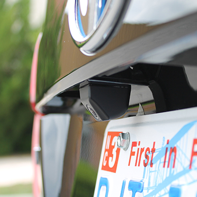 The rear license plate area of a car with a backup camera as the main focus point.