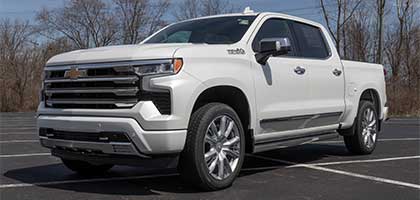 An image showing a white Chevrolet Silverado 1500 in a parking lot.