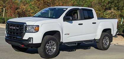 An image showing a white GMC Canyon truck in a parking lot.